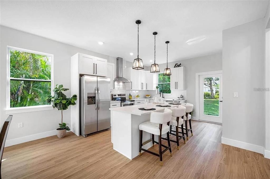 A modern kitchen features white cabinetry, stainless steel appliances, and a large central island — 1516 59TH STREET N, ST PETERSBURG, FL