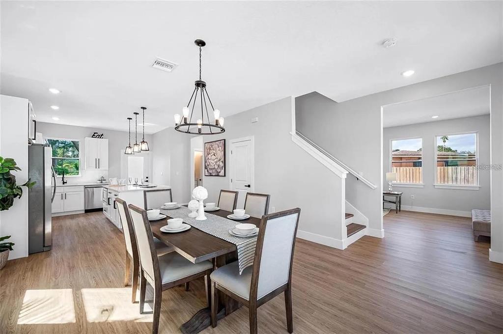A dining area with a wooden table and chairs sits adjacent to a white kitchen — 1516 59TH STREET N, ST PETERSBURG, FL