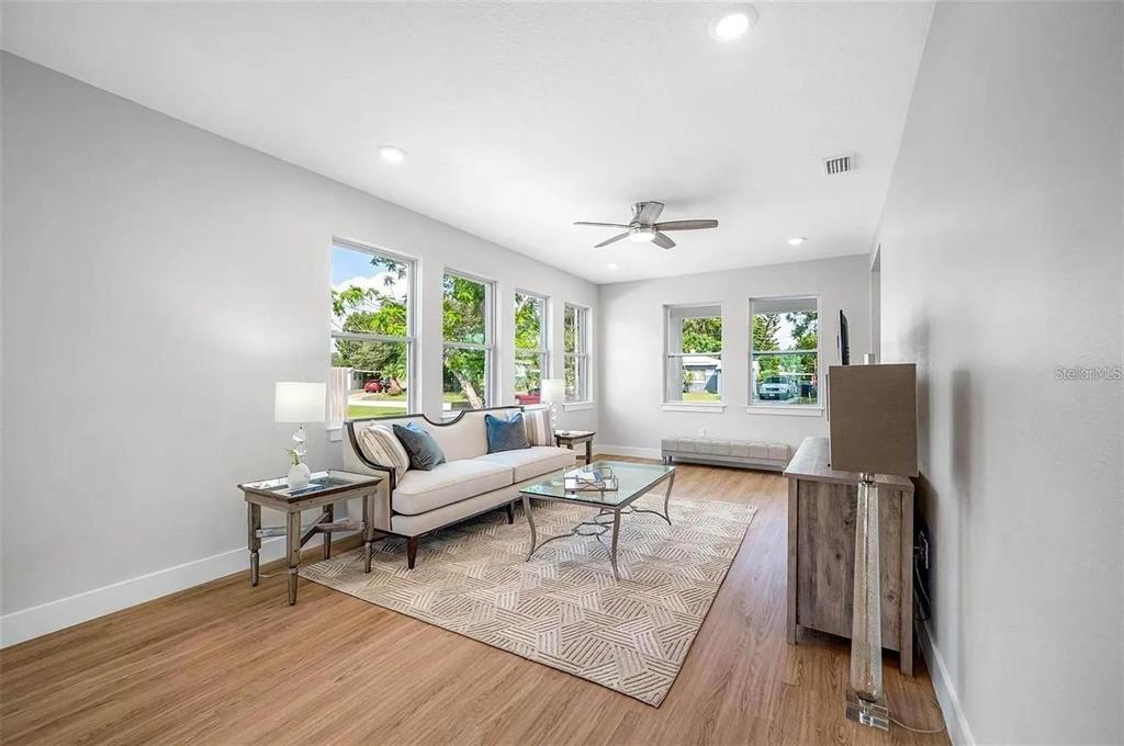 A living room with light wood floors, a sofa, a coffee table, and large windows — 1516 59TH STREET N, ST PETERSBURG, FL