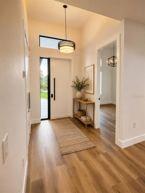 A bright entryway features wood-look flooring, a modern pendant light, and a white front door — 32 SALUDA TERRACE, PORT CHARLOTTE, FL