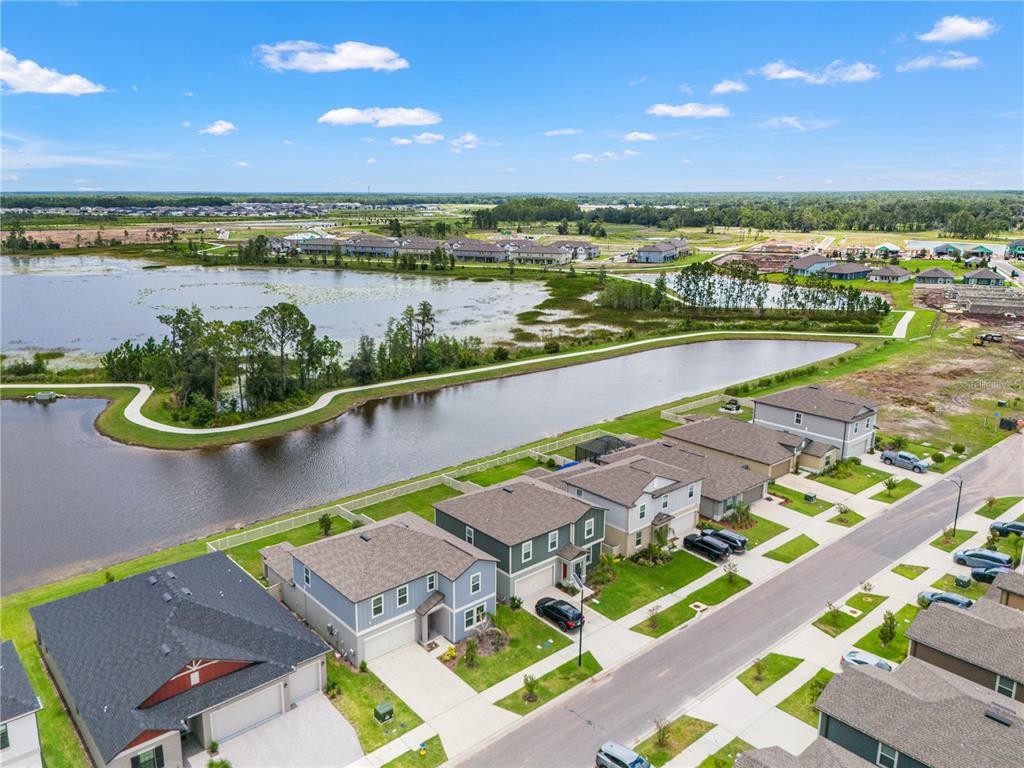 An aerial view shows a suburban neighborhood with houses bordering a large retention pond — 22313 PLEASANT MORNING DRIVE, LAND O LAKES, FL