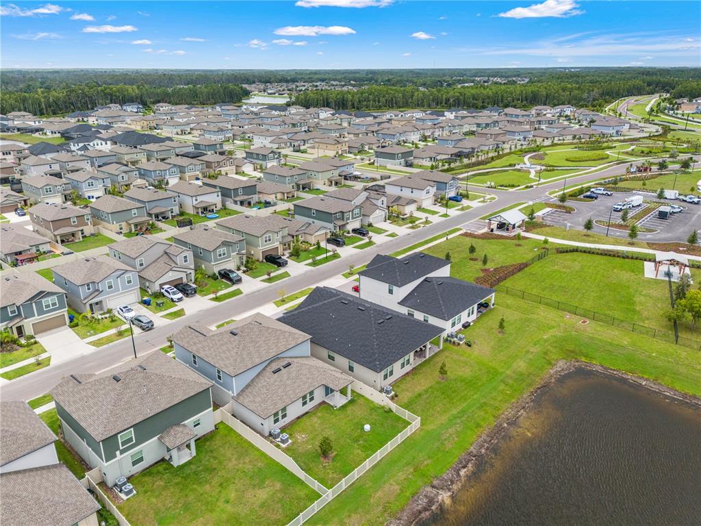 An aerial view shows a suburban neighborhood with houses, a pond, and a parking lot — 22313 PLEASANT MORNING DRIVE, LAND O LAKES, FL
