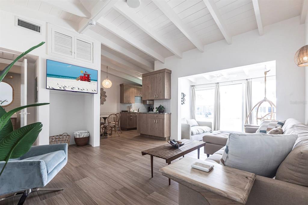 A living room with wood-look tile floors, vaulted ceilings, and an open kitchen area — 6006 MIDNIGHT PASS ROAD UNIT 53, SARASOTA, FL