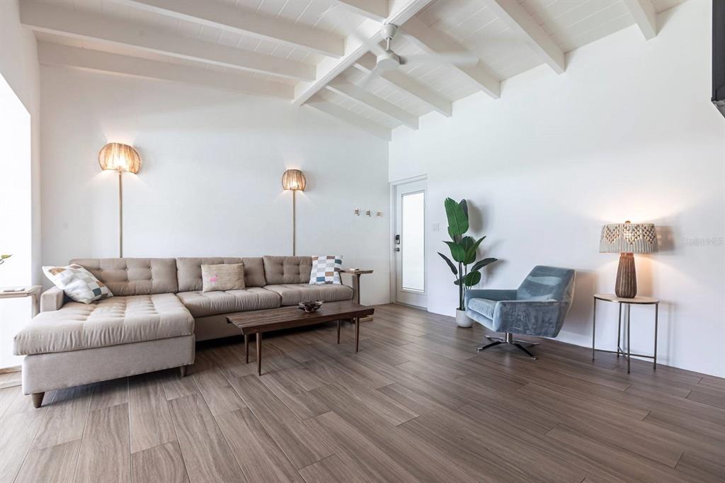 A living room features a sectional sofa, a blue armchair, and vaulted wood-beamed ceilings — 6006 MIDNIGHT PASS ROAD UNIT 53, SARASOTA, FL