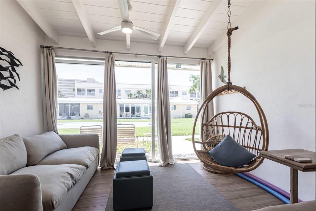A sunroom features a sofa, a hanging rattan chair, and sliding glass doors to outside — 6006 MIDNIGHT PASS ROAD UNIT 53, SARASOTA, FL