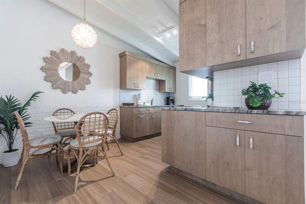 A kitchen and dining area with light wood cabinets, white tile backsplashes, and rattan chairs — 6006 MIDNIGHT PASS ROAD UNIT 53, SARASOTA, FL