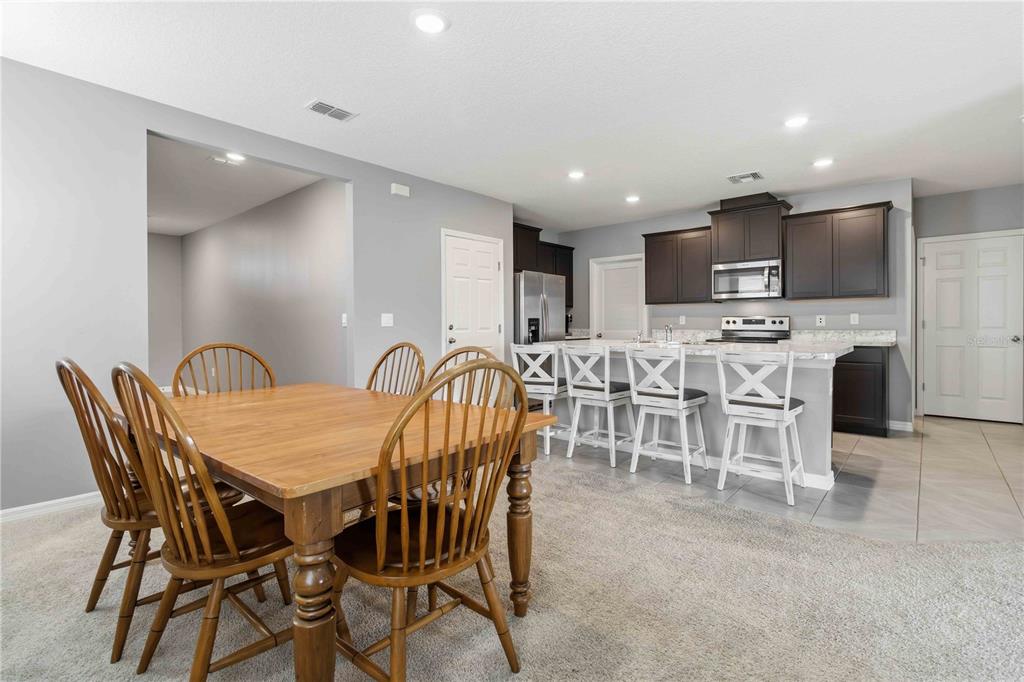 A dining area with a wooden table and chairs sits adjacent to a kitchen with island seating — 1156 VALLEY VIEW AVENUE, ROCKLEDGE, FL
