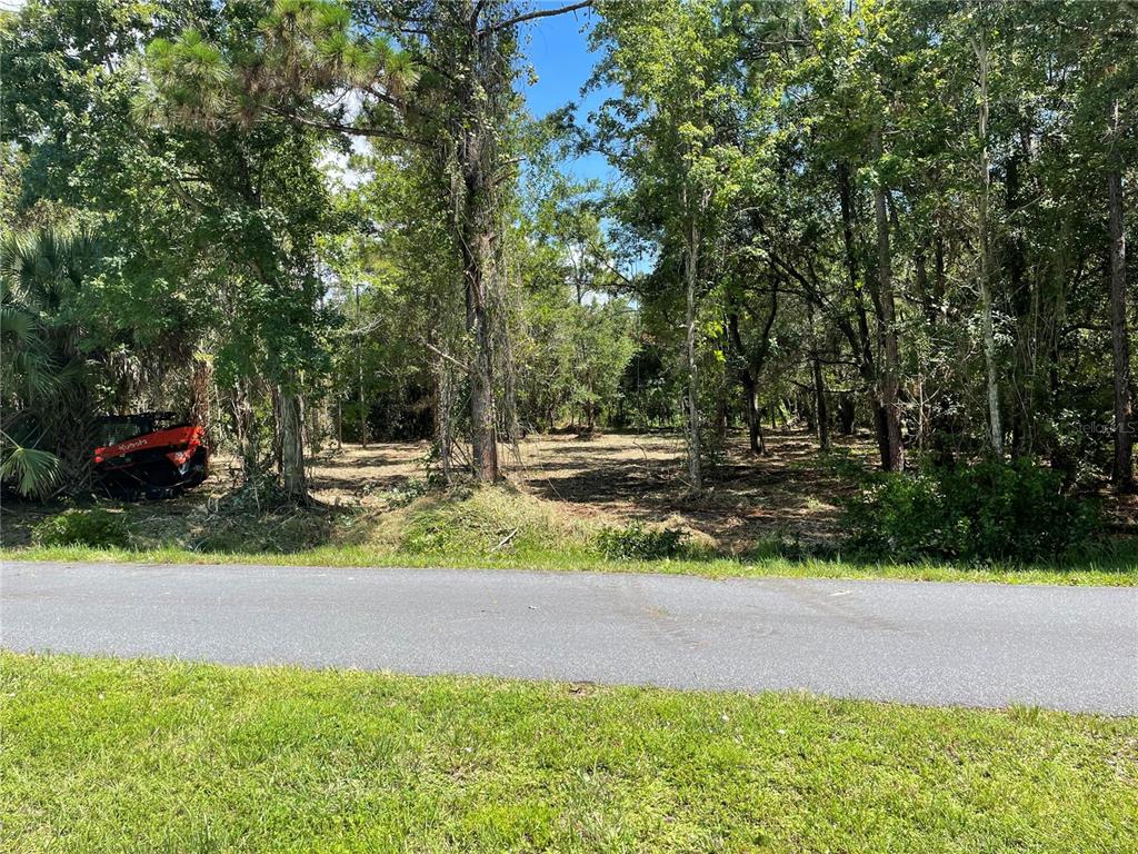 A cleared, wooded residential lot sits behind a paved road with a small orange tractor — 3165 STEWART BOULEVARD, KISSIMMEE, FL
