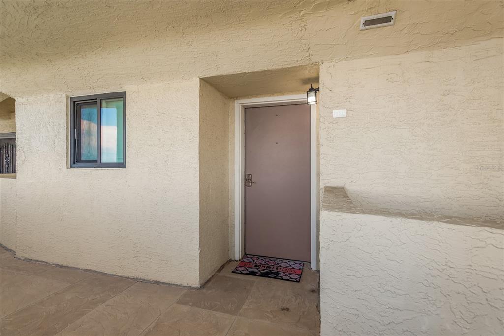 A beige stucco exterior wall features a single entry door and a small window — 5915 SEA RANCH DRIVE UNIT 503, HUDSON, FL