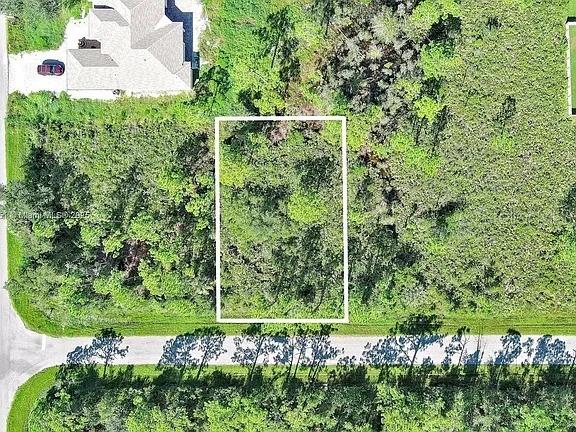 An aerial view shows a rectangular vacant lot outlined in white next to a house — 105 MORDECAL STREET, PORT CHARLOTTE, FL