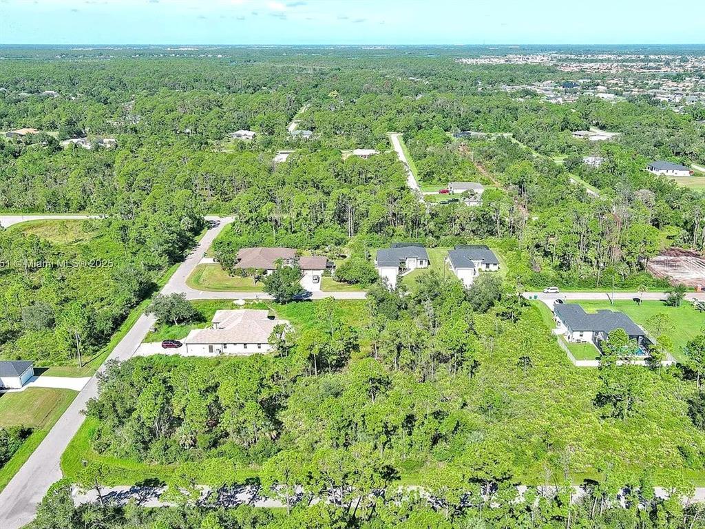 An aerial view shows several houses surrounded by dense trees and vegetation in a neighborhood — 105 MORDECAL STREET, PORT CHARLOTTE, FL