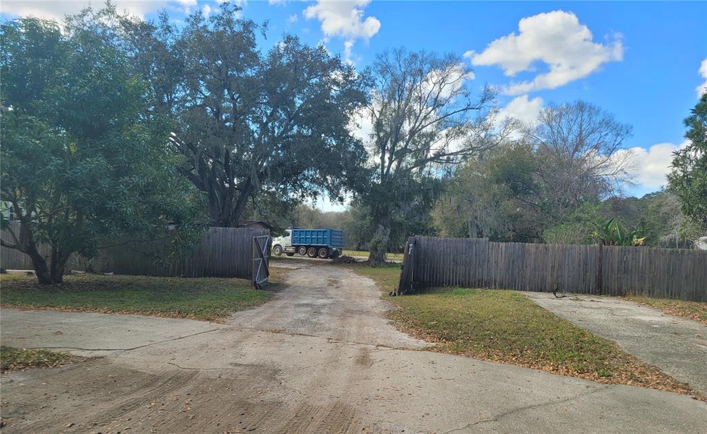 A gravel driveway leads through an open wooden fence toward a blue dump truck — 0 BUCKLEY DRIVE, KISSIMMEE, FL