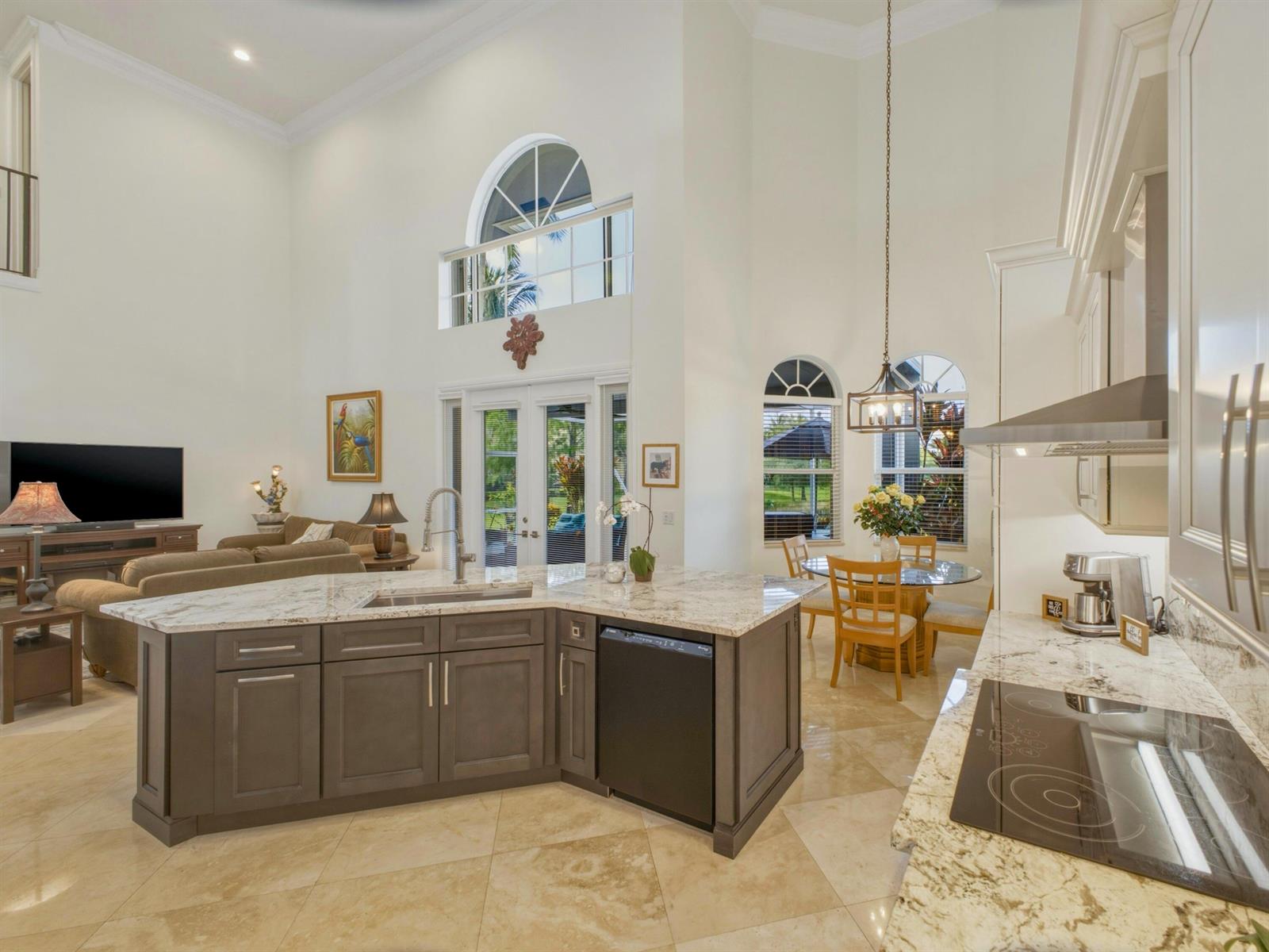 A kitchen with a dark island, granite countertops, and a dining area under high ceilings — 9814 Coronado Lake Drive, Boynton Beach FL 33437, BOYNTON BEACH, FL