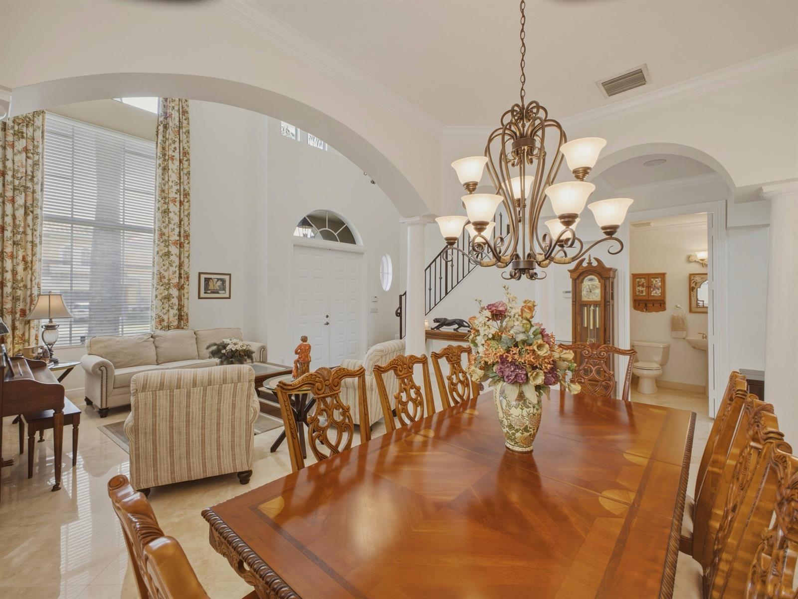A dining room with a wooden table and chandelier opens into a living area — 9814 Coronado Lake Drive, Boynton Beach FL 33437, BOYNTON BEACH, FL