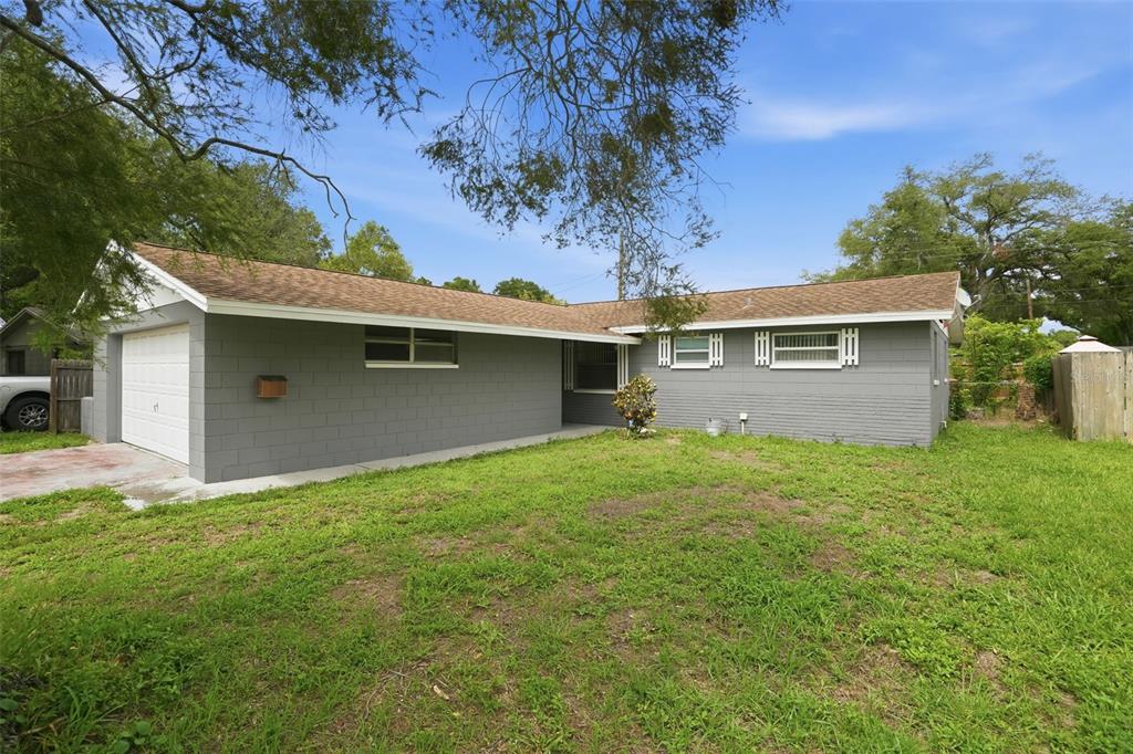 A single-story gray concrete block house with a white garage door and brown roof — 8855 53RD WAY N, PINELLAS PARK, FL