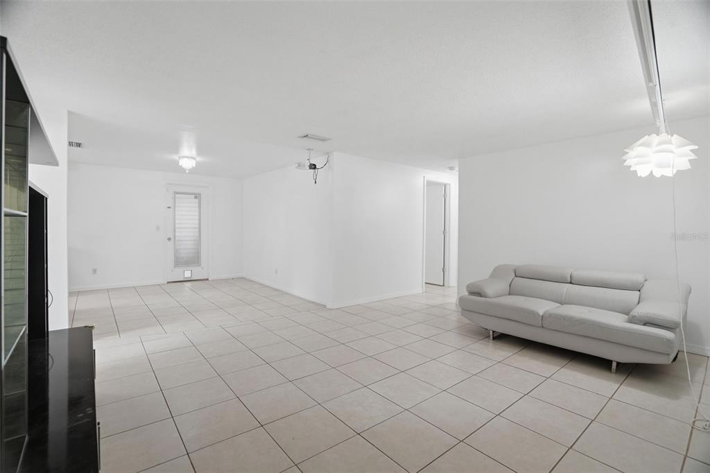 A bright, open-concept living room features white walls, light-colored floor tiles, and a white sofa — 8855 53RD WAY N, PINELLAS PARK, FL