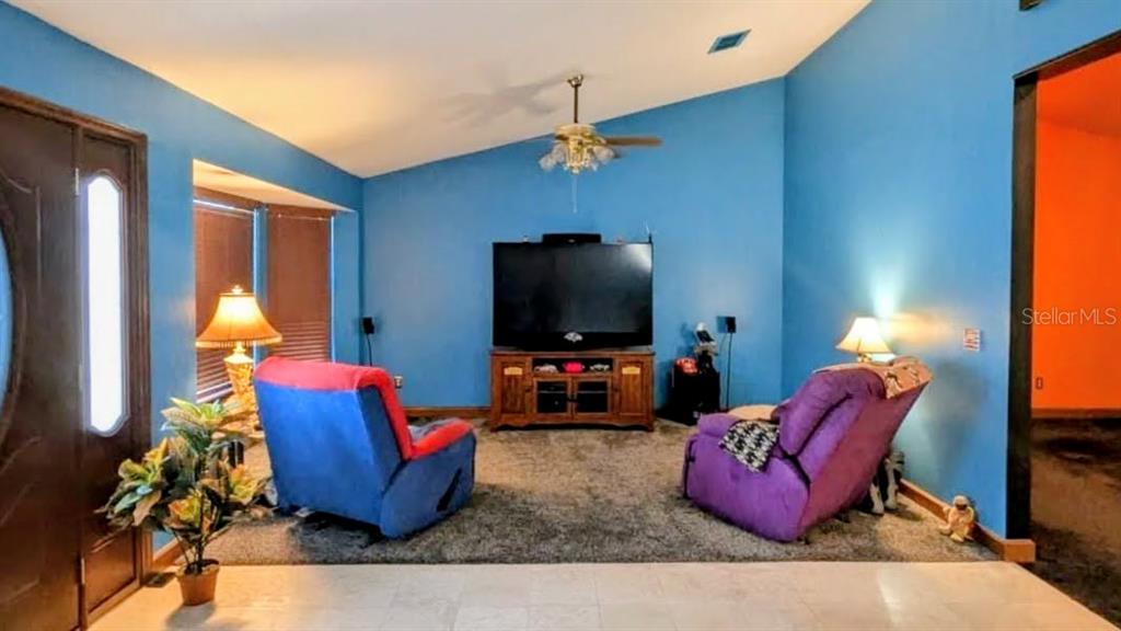 A living room features blue walls, a vaulted ceiling, a television console, and two recliners — 2220 EMPEROR DRIVE, KISSIMMEE, FL