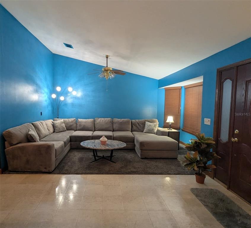 A living room features blue walls, a large sectional sofa, and a tile floor — 2220 EMPEROR DRIVE, KISSIMMEE, FL