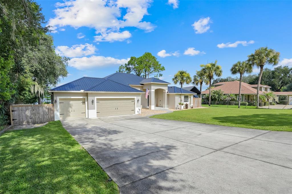 An aerial view of a single-story house with a metal roof, garage, and waterfront backyard — 18233 ROSE STREET, GROVELAND, FL