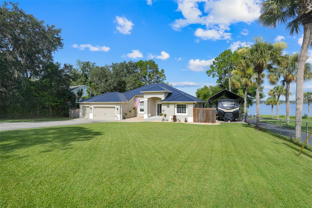An aerial view shows a house with a dark roof on a lakefront lot — 18233 ROSE STREET, GROVELAND, FL