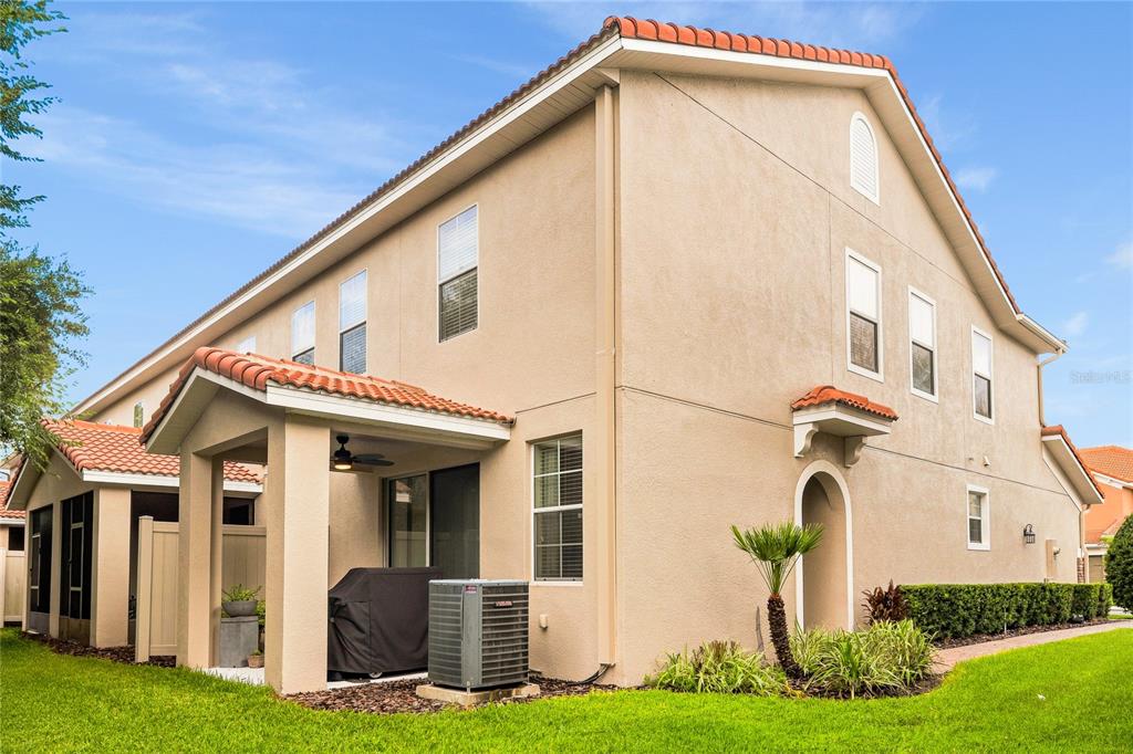 The exterior of a two-story beige stucco house features a covered patio and tiled roof — 5369 VIA APPIA WAY, SANFORD, FL