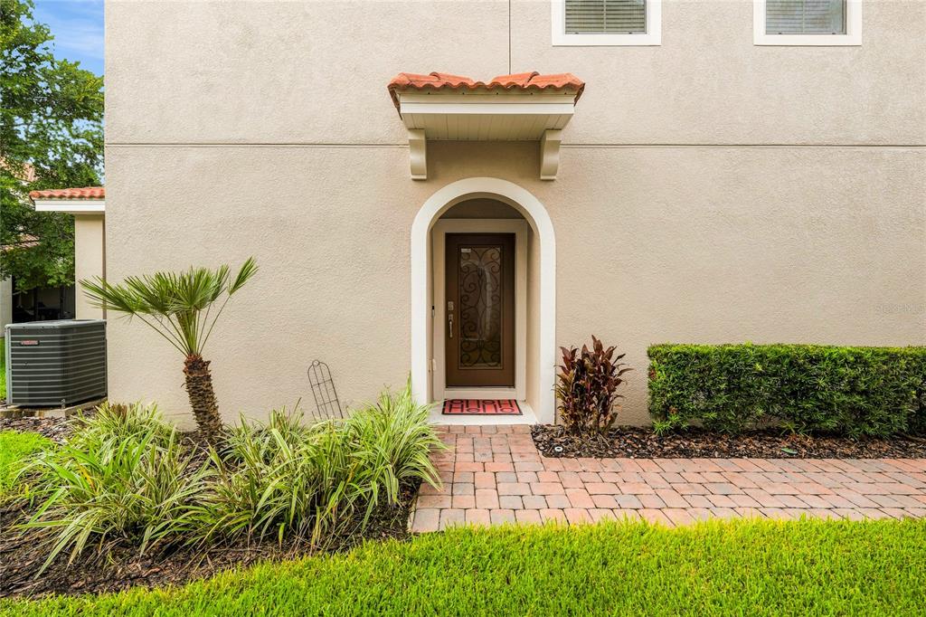 The exterior of a beige stucco house features an arched front door with a decorative awning — 5369 VIA APPIA WAY, SANFORD, FL