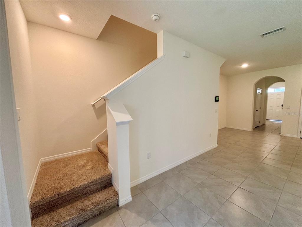 An interior view shows a carpeted staircase next to a tiled hallway leading to a doorway — 401 FELTRIM RESERVE BOULEVARD, DAVENPORT, FL