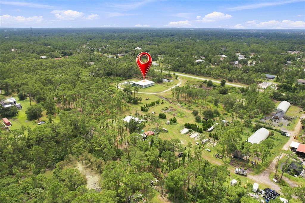 An aerial view shows a house with a large screened porch surrounded by wooded land — 8146 TROPICAIRE BOULEVARD, NORTH PORT, FL