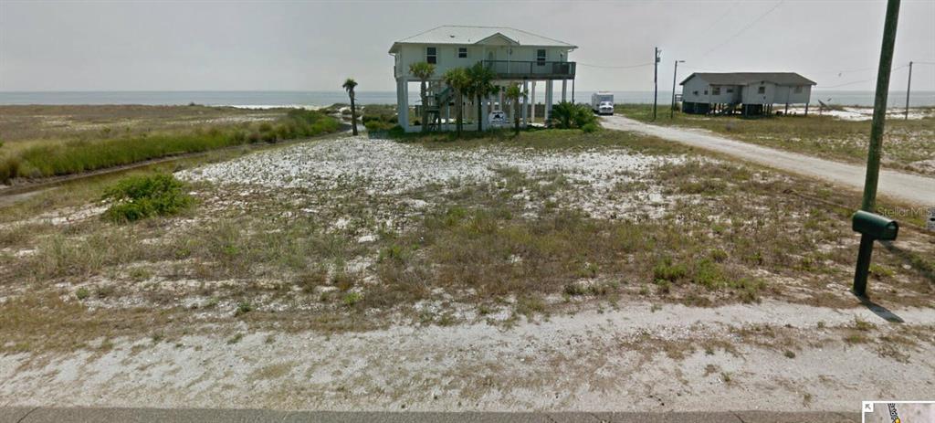 A vacant sandy lot sits in front of two elevated houses near the ocean — 3 MARLIN STREET, PANACEA, FL