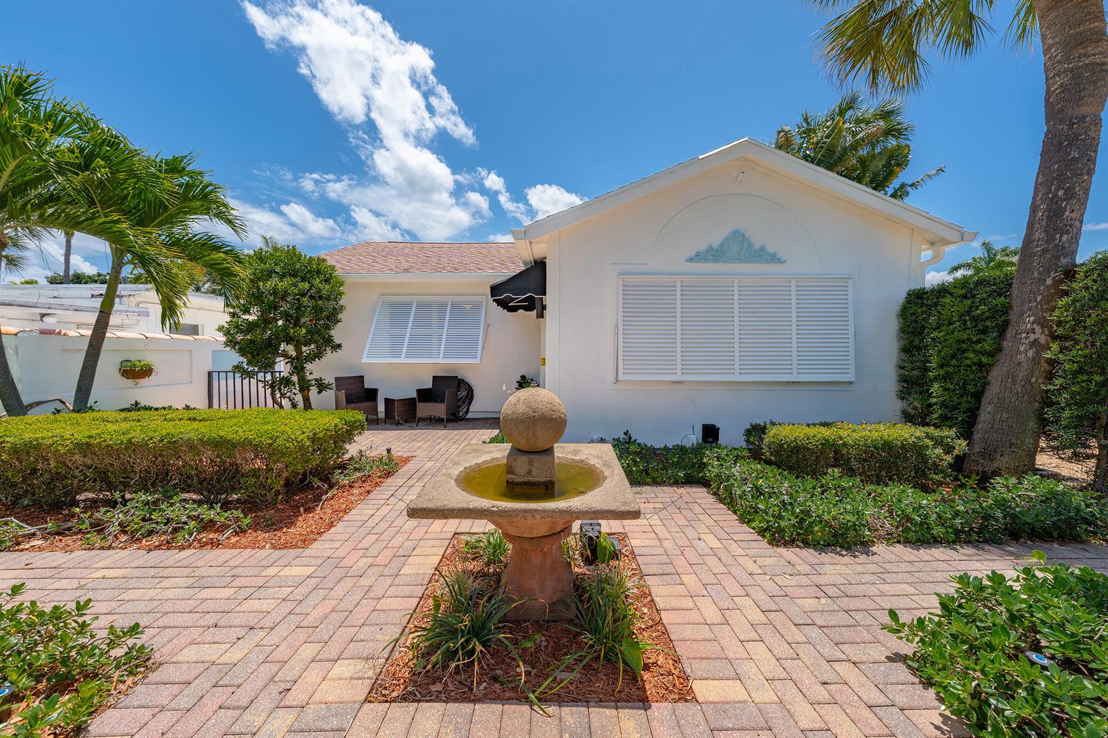 A stone fountain sits on a brick patio in front of a white house — 205 N 18th Ave Avenue N, FL 33460, FL