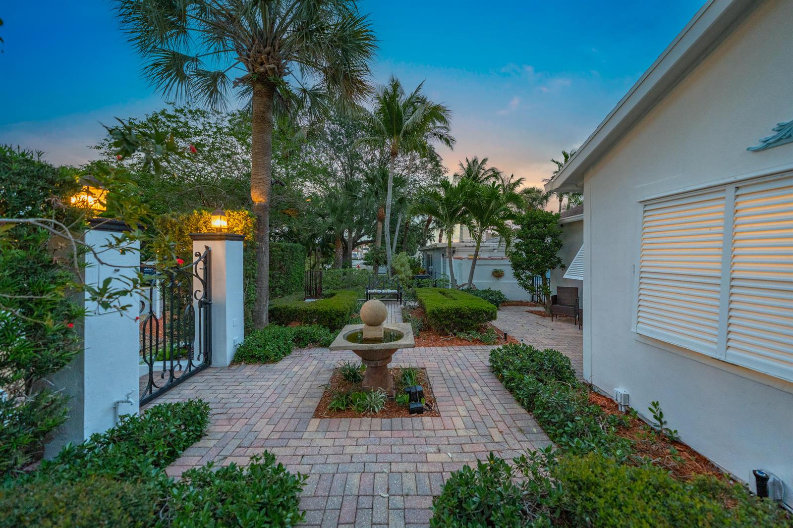 A stone fountain sits in the center of a brick courtyard beside a white house — 205 N 18th Ave Avenue N, FL 33460, FL