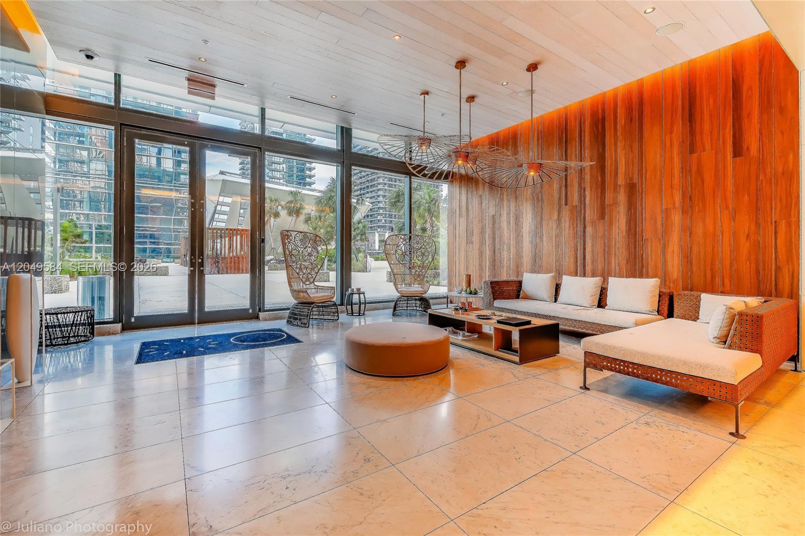 A modern lobby features a wood-paneled wall, large windows, and contemporary lounge seating — 88 SW 7th St # 2401, Miami FL 33130, MIAMI, FL