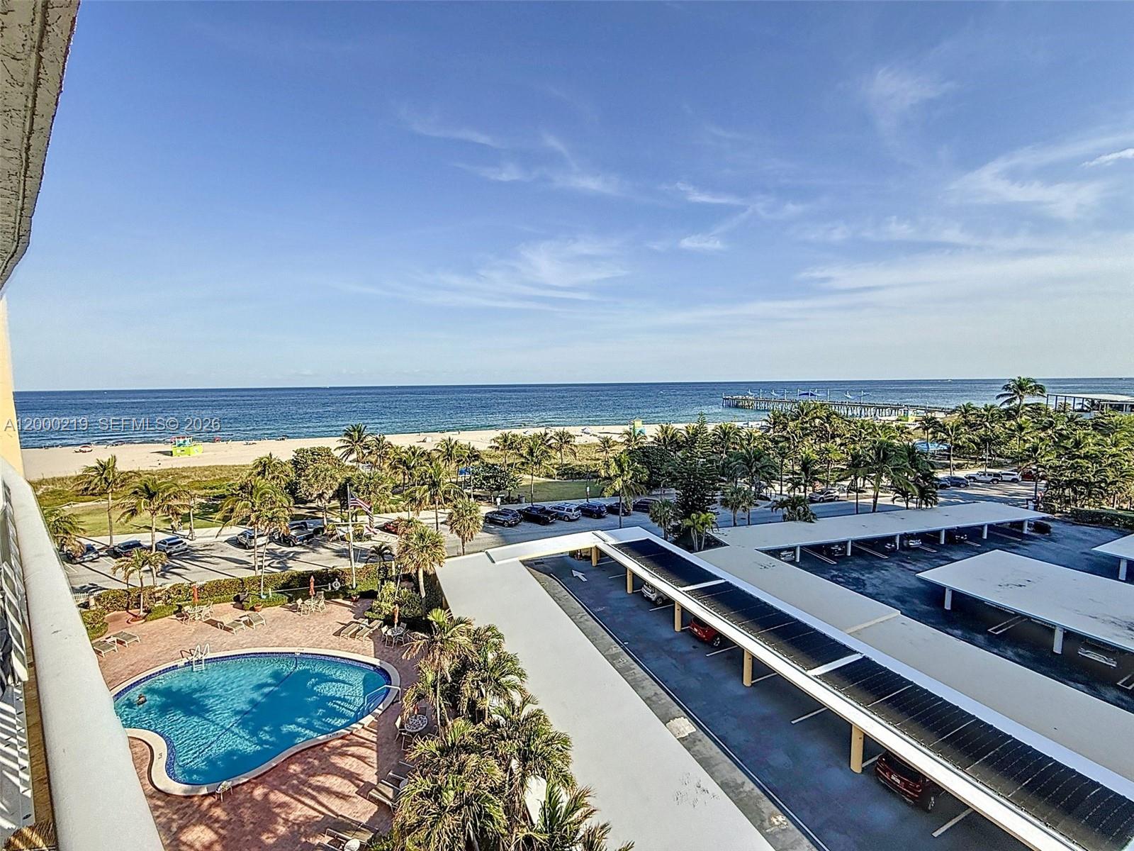 An elevated view shows a swimming pool, covered parking, palm trees, and a sandy beach — 328 N Ocean Blvd # 707, Pompano Beach FL 33062, POMPANO BEACH, FL