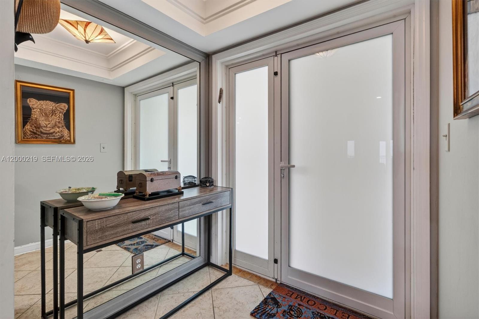 An entryway features a console table, a large wall mirror, and frosted glass double doors — 328 N Ocean Blvd # 707, Pompano Beach FL 33062, POMPANO BEACH, FL