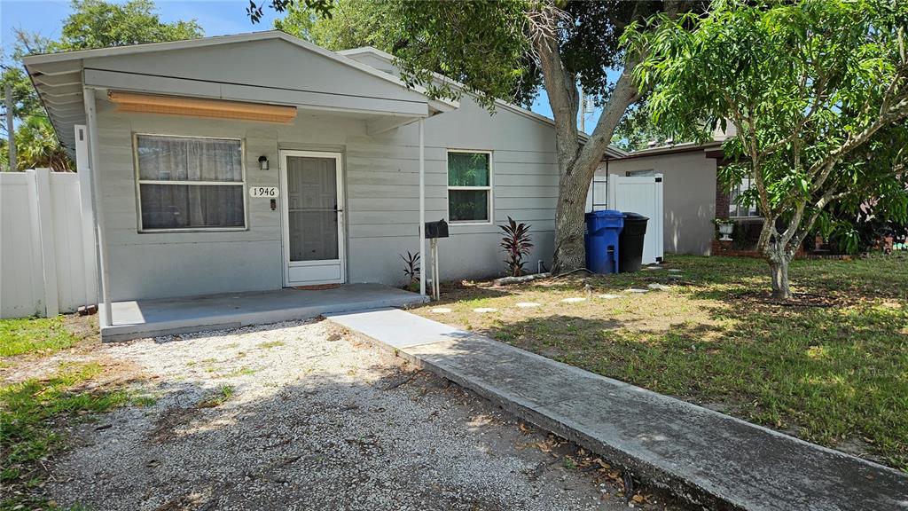 A single-story gray house with a front porch, a gravel driveway, and a concrete walkway — 1946 15TH AVENUE S, ST PETERSBURG, FL