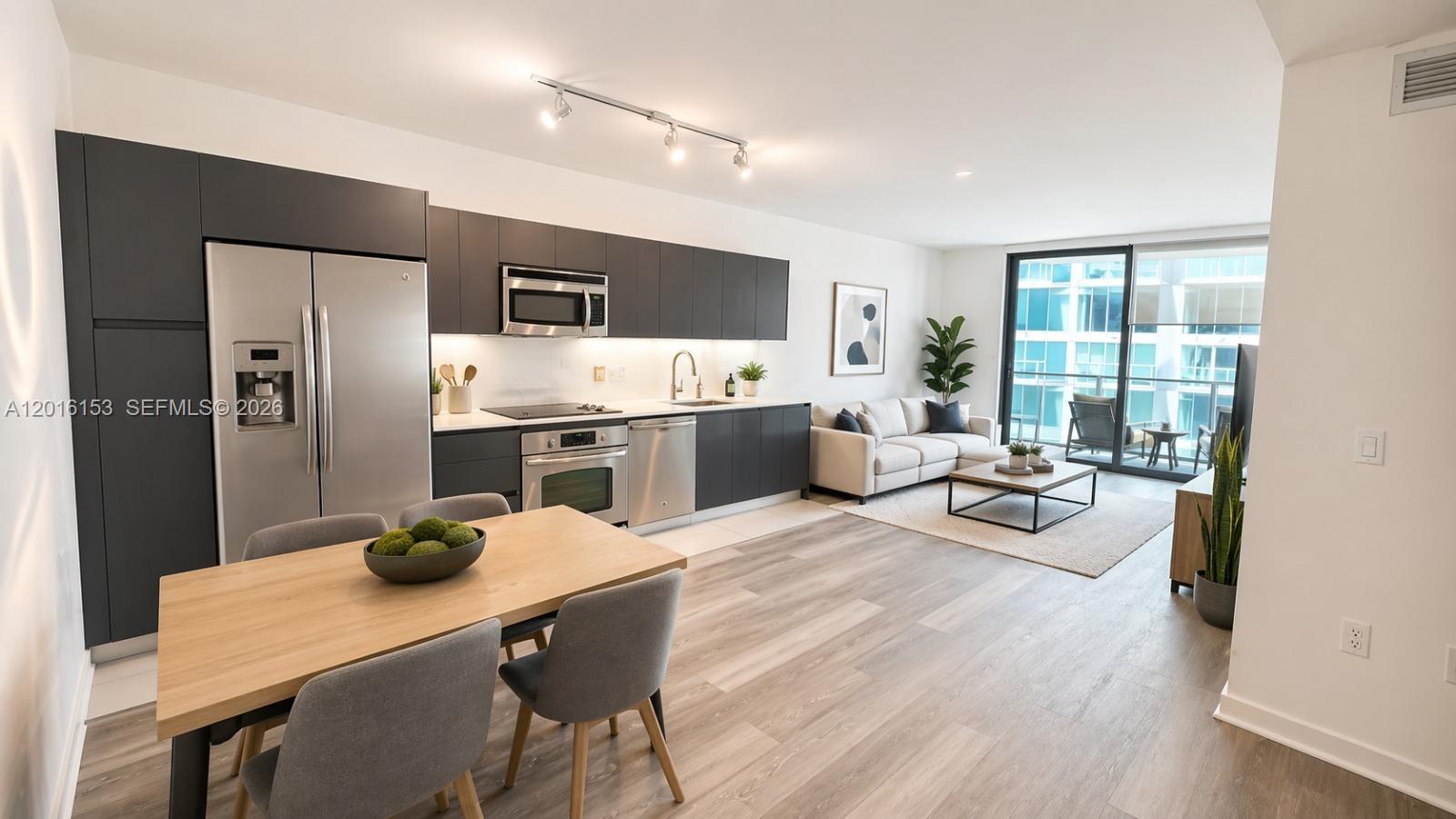An open-concept apartment features a modern kitchen with dark cabinetry, dining area, and living room — 31 SE 6th St # 1904, Miami FL 33131, MIAMI, FL