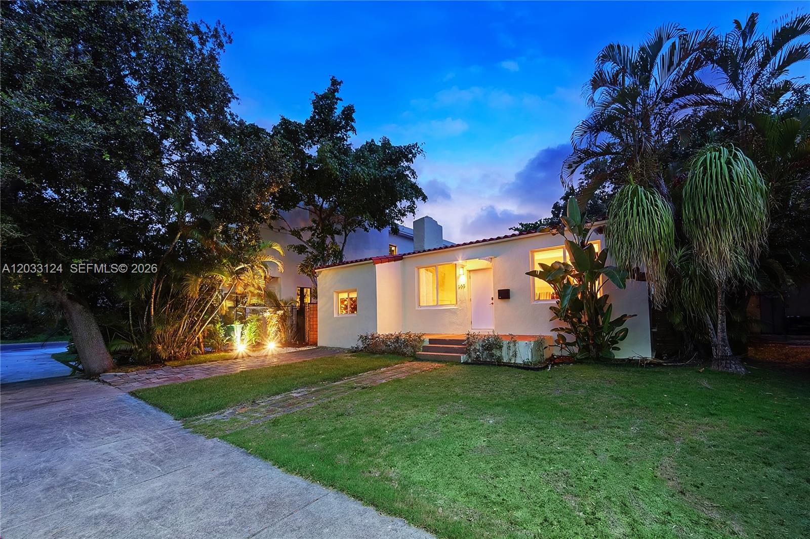 A single-story house with a white stucco exterior and a red tile roof at dusk — 565 NW 44th St, Miami FL 33127, MIAMI, FL