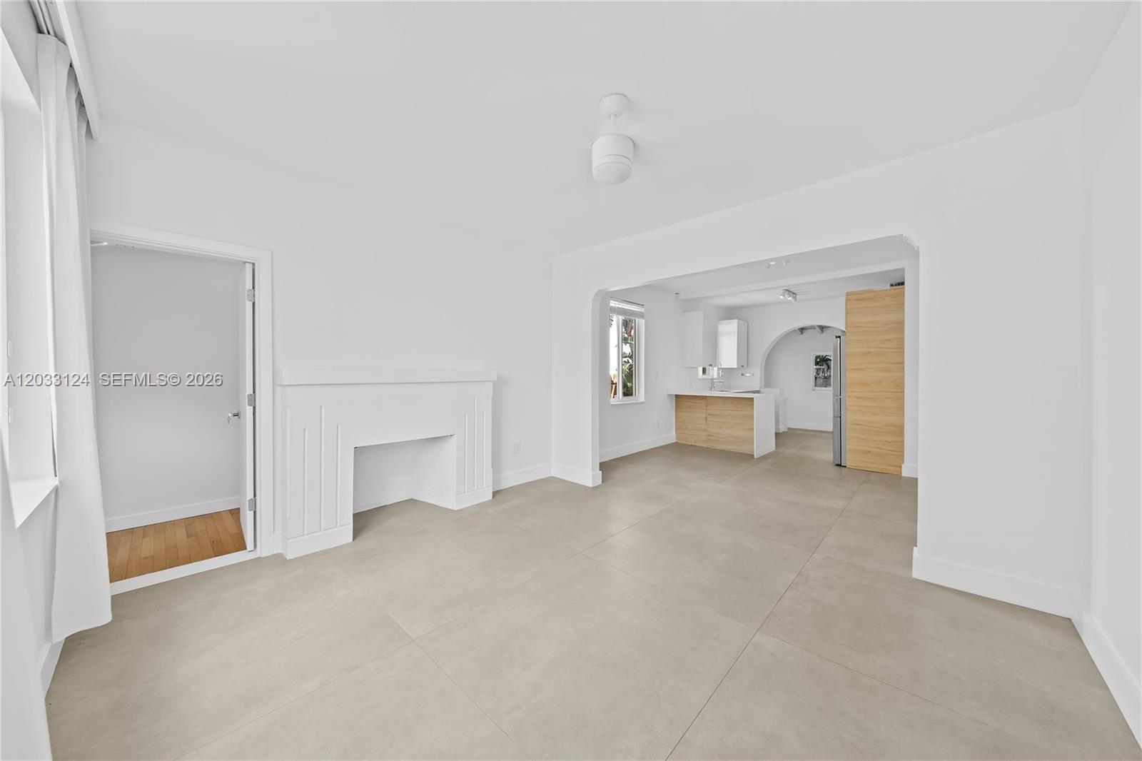 A bright living room features a white fireplace, tile flooring, and an open kitchen — 565 NW 44th St, Miami FL 33127, MIAMI, FL
