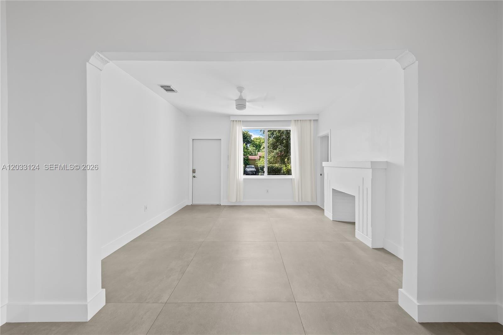 A bright living room features white walls, large gray floor tiles, and a white fireplace — 565 NW 44th St, Miami FL 33127, MIAMI, FL