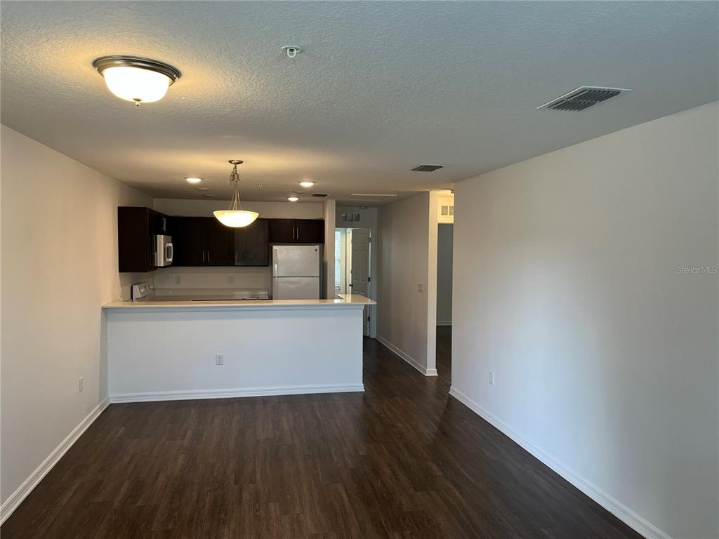 A kitchen with dark cabinets and a breakfast bar overlooks an open living area — 295 FLOWER LANE UNIT F, KISSIMMEE, FL