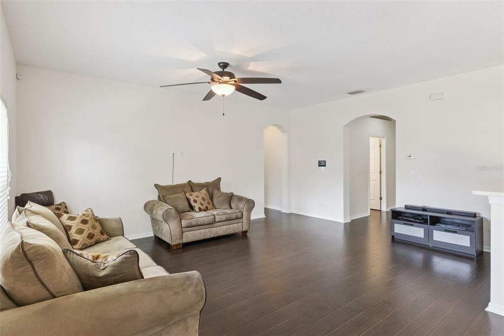 A living room with dark wood flooring, beige sofas, and a ceiling fan — 725 STAR POINTE DRIVE, SEFFNER, FL