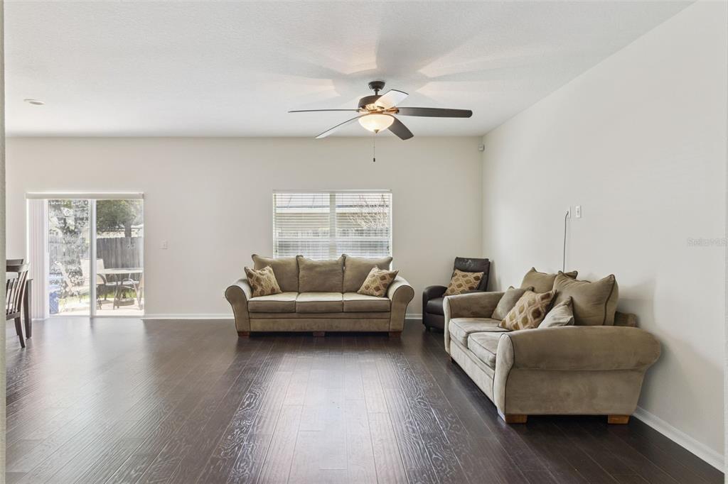 A living room features dark wood flooring, two beige sofas, and a ceiling fan — 725 STAR POINTE DRIVE, SEFFNER, FL