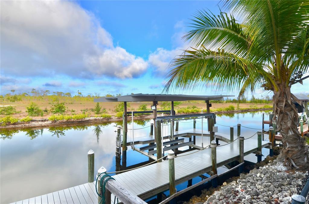 A wooden boat dock with a covered lift extends into a calm canal — 3605 STABILE ROAD, ST JAMES CITY, FL