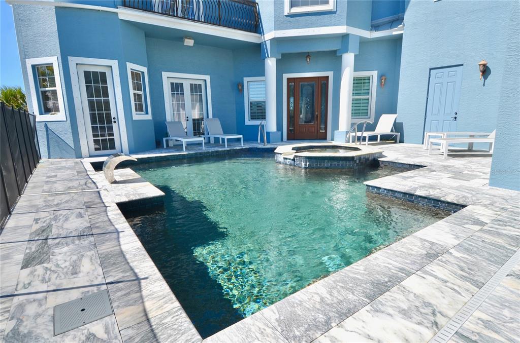 A blue house exterior features a swimming pool with an integrated hot tub and patio — 3605 STABILE ROAD, ST JAMES CITY, FL