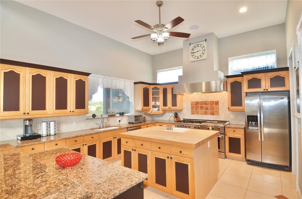 A kitchen features light wood cabinets with dark panels, granite countertops, and a central island — 3605 STABILE ROAD, ST JAMES CITY, FL