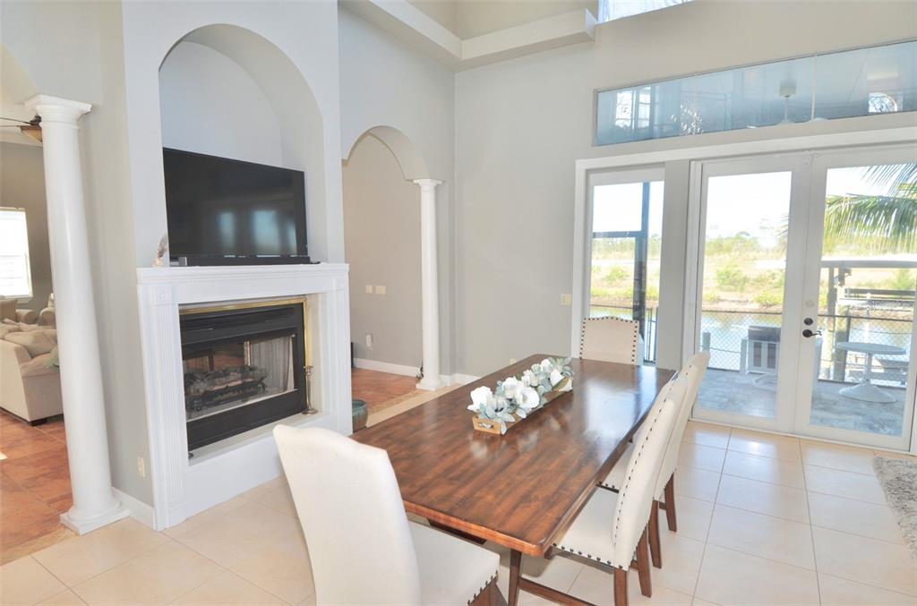 A dining room features a wooden table, white chairs, a fireplace, and glass patio doors — 3605 STABILE ROAD, ST JAMES CITY, FL