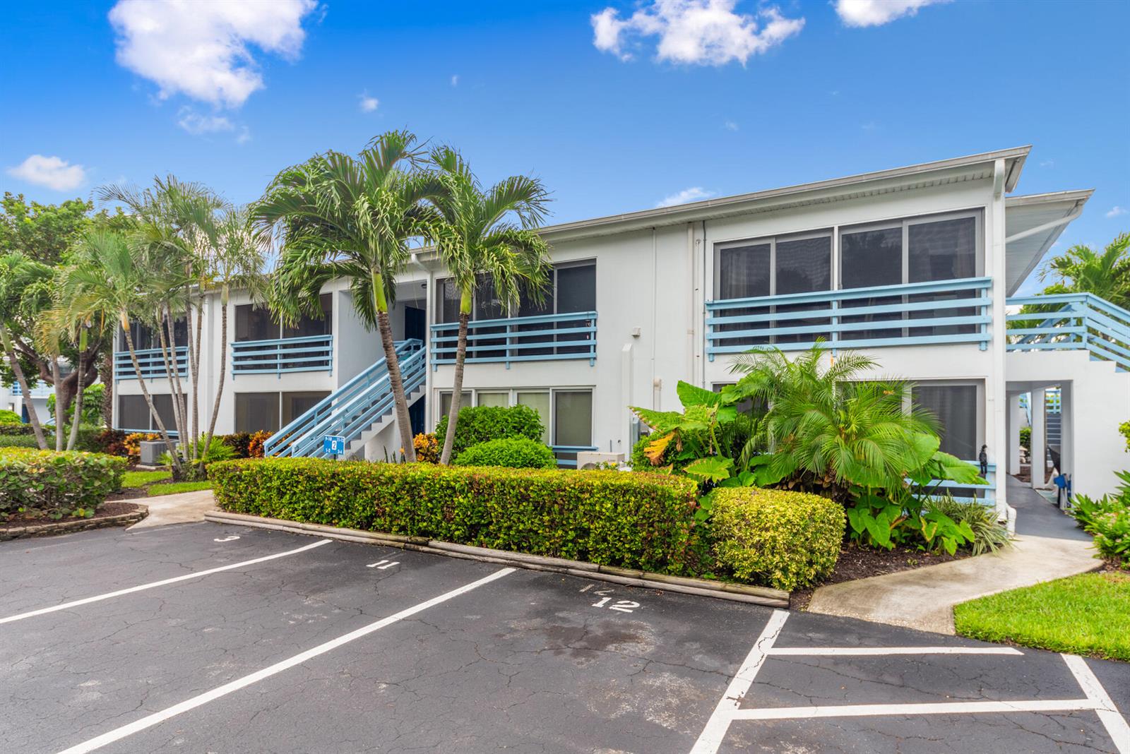 A two-story apartment building features white siding, blue railings, and a parking lot in front — 11000 S Ocean Drive # 2, Jensen Beach FL 34957, JENSEN BEACH, FL