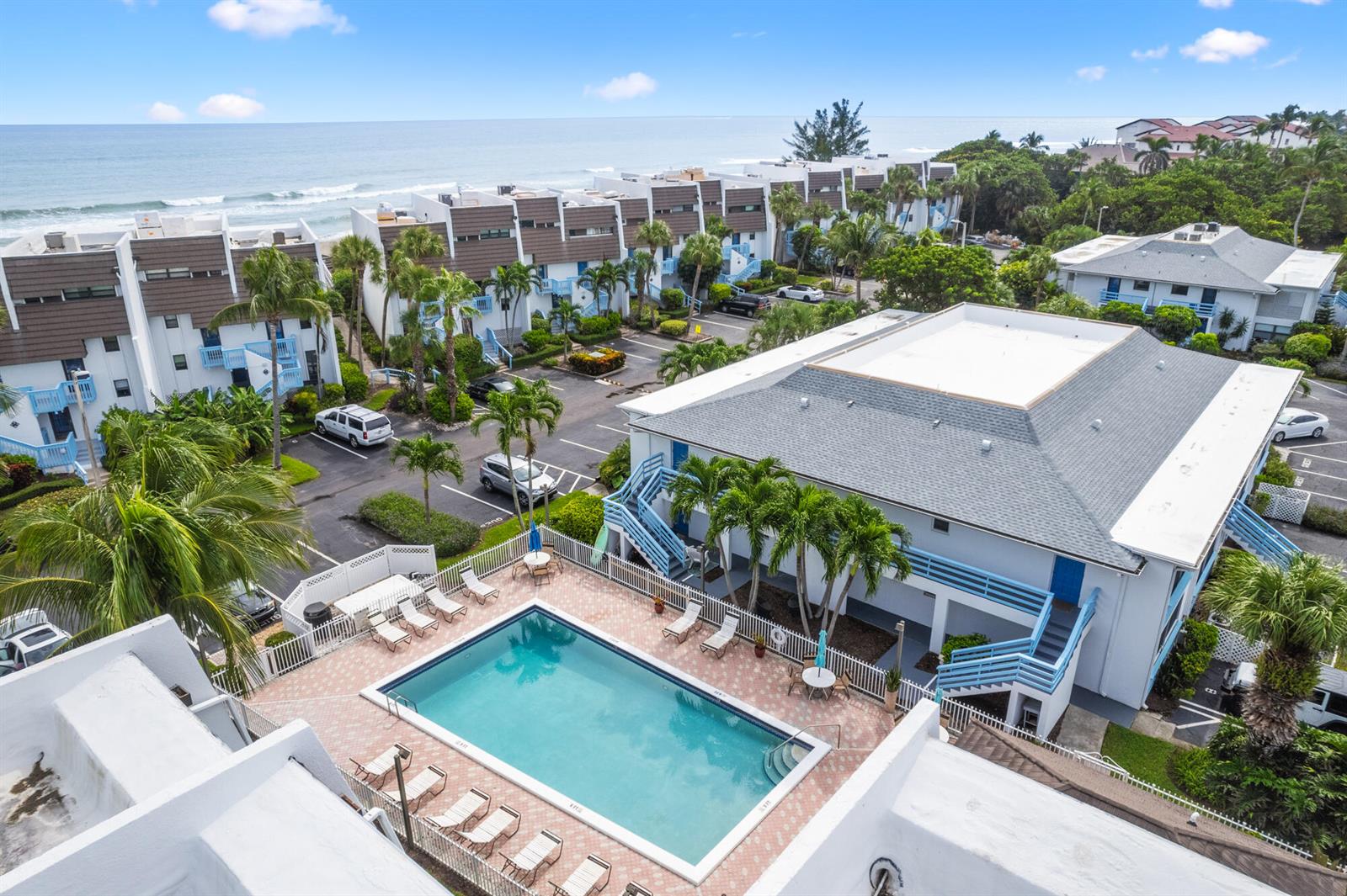 An aerial view shows a swimming pool, parking lot, and multi-story buildings near the ocean — 11000 S Ocean Drive # 2, Jensen Beach FL 34957, JENSEN BEACH, FL