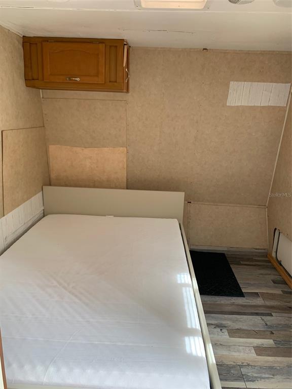 A bedroom in a recreational vehicle features a bed, wood-toned cabinetry, and wood-look flooring — 3000 CLARCONA ROAD UNIT 333, APOPKA, FL