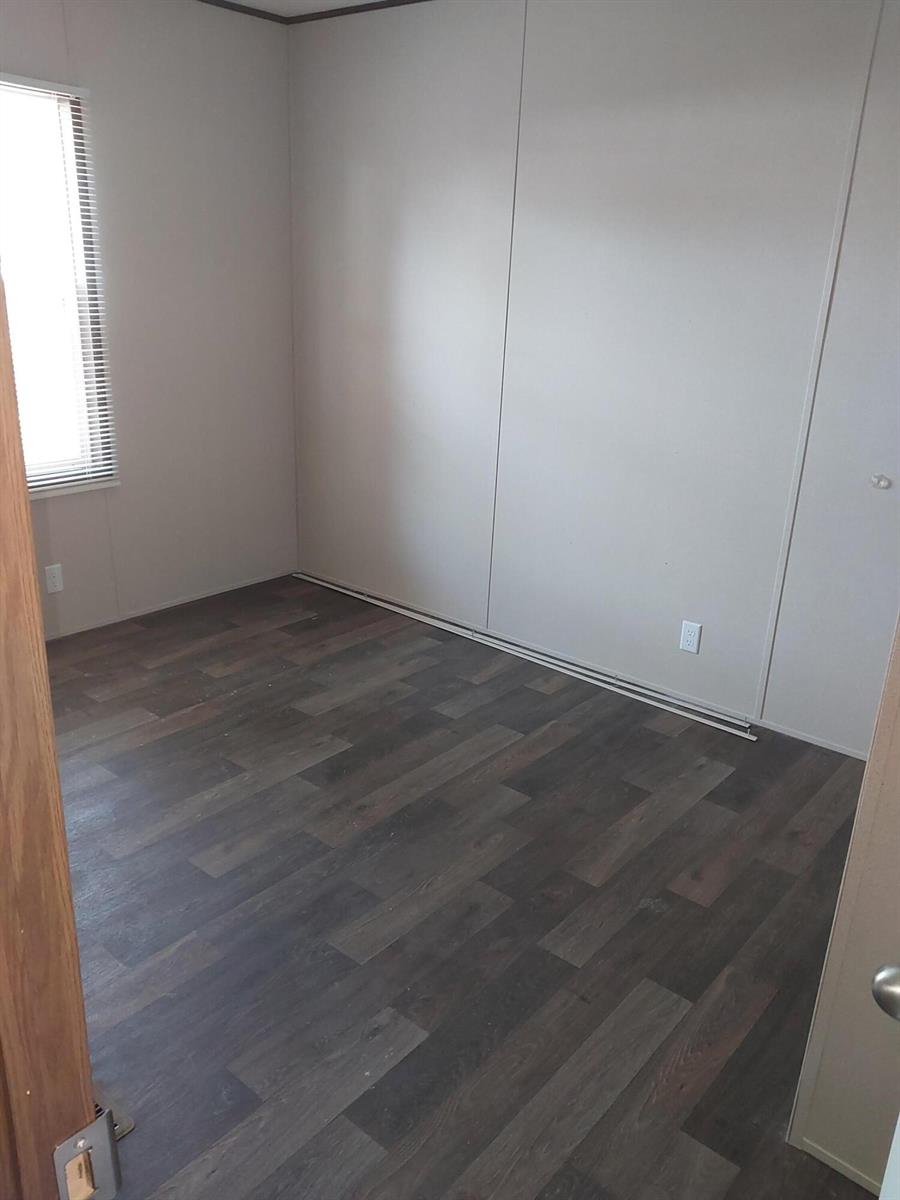 An empty bedroom features light-colored walls, dark wood-look flooring, and a single window with blinds — 506 SE San Jose Street, Stuart FL 34994, STUART, FL